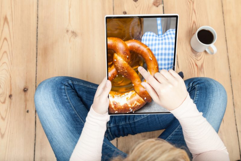 Frau sitzt mit Tablet auf Schoß und tippt auf Screen