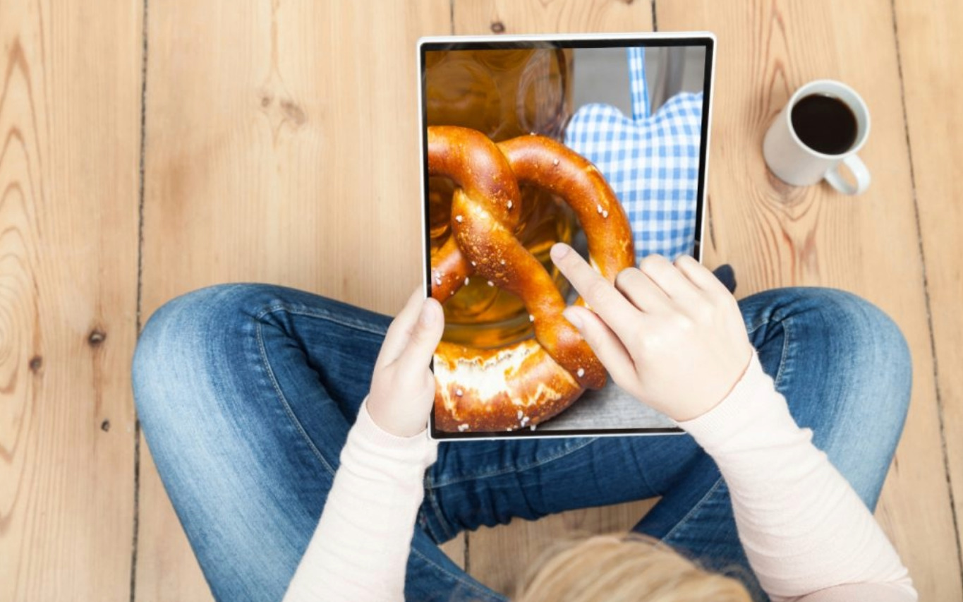 Finger zeigt auf Brezel, der auf Screen von Tablet ist